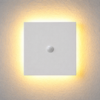 Square white outdoor wall sconce with a central sensor and warm halo on a light wall.