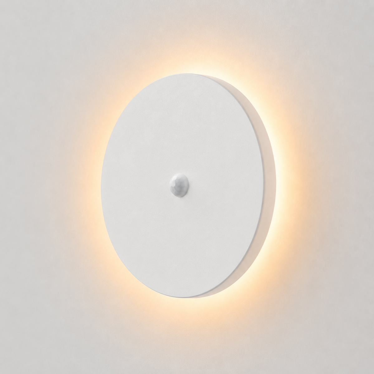 Round white outdoor wall sconce with a central sensor and warm backlit glow on a light wall.