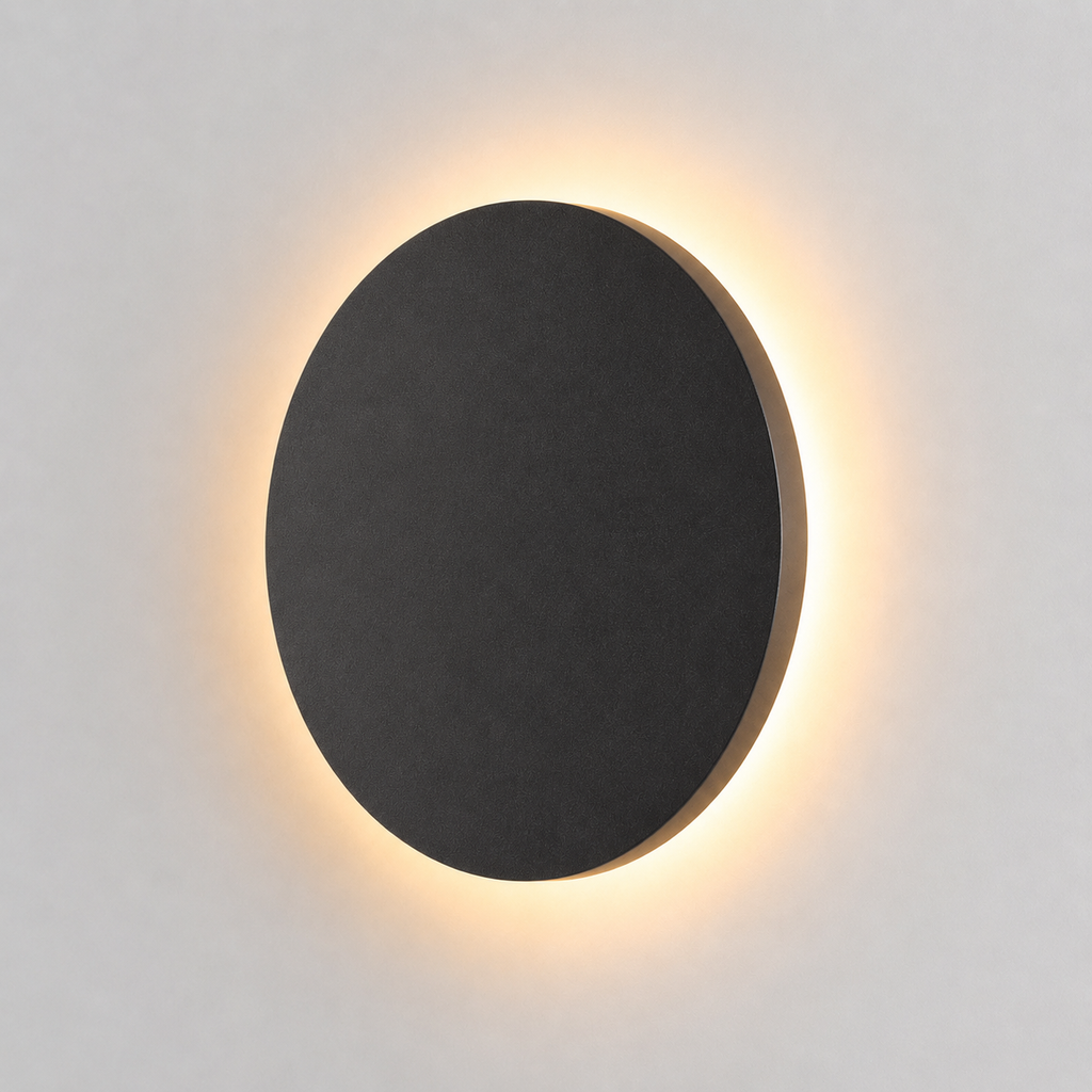 Black round outdoor wall light glowing with a warm halo against a plain light background.
