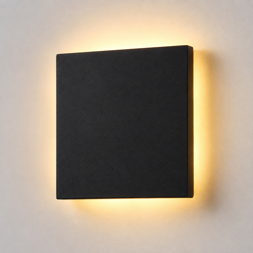 Square black outdoor wall sconce shown at an angle with warm light glowing around the edges.