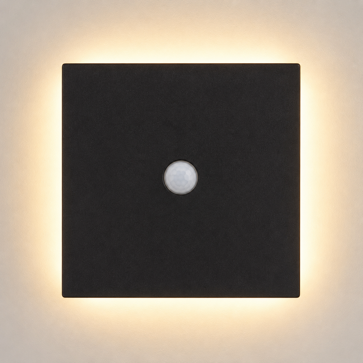 Square black outdoor wall sconce with a central sensor and warm halo on a light wall.
