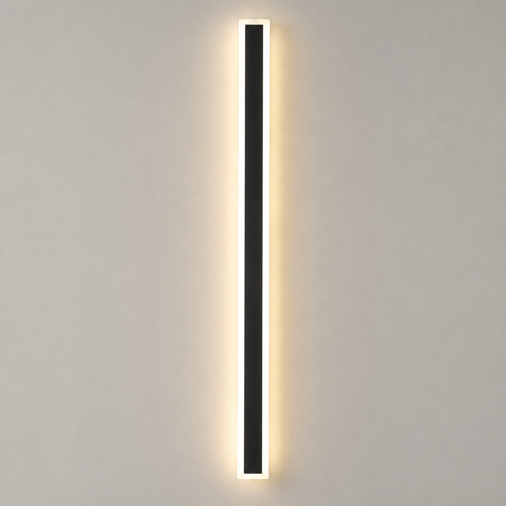 Outdoor wall sconce with a slim black vertical body glowing warm against a light gray wall.
