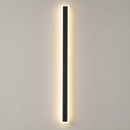 Outdoor wall sconce with a slim black vertical body glowing warm against a light gray wall.