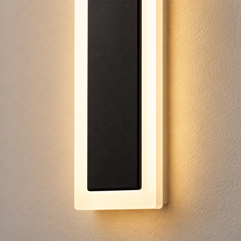 Outdoor wall sconce close-up showing a black center panel, pale frame, and warm side glow.