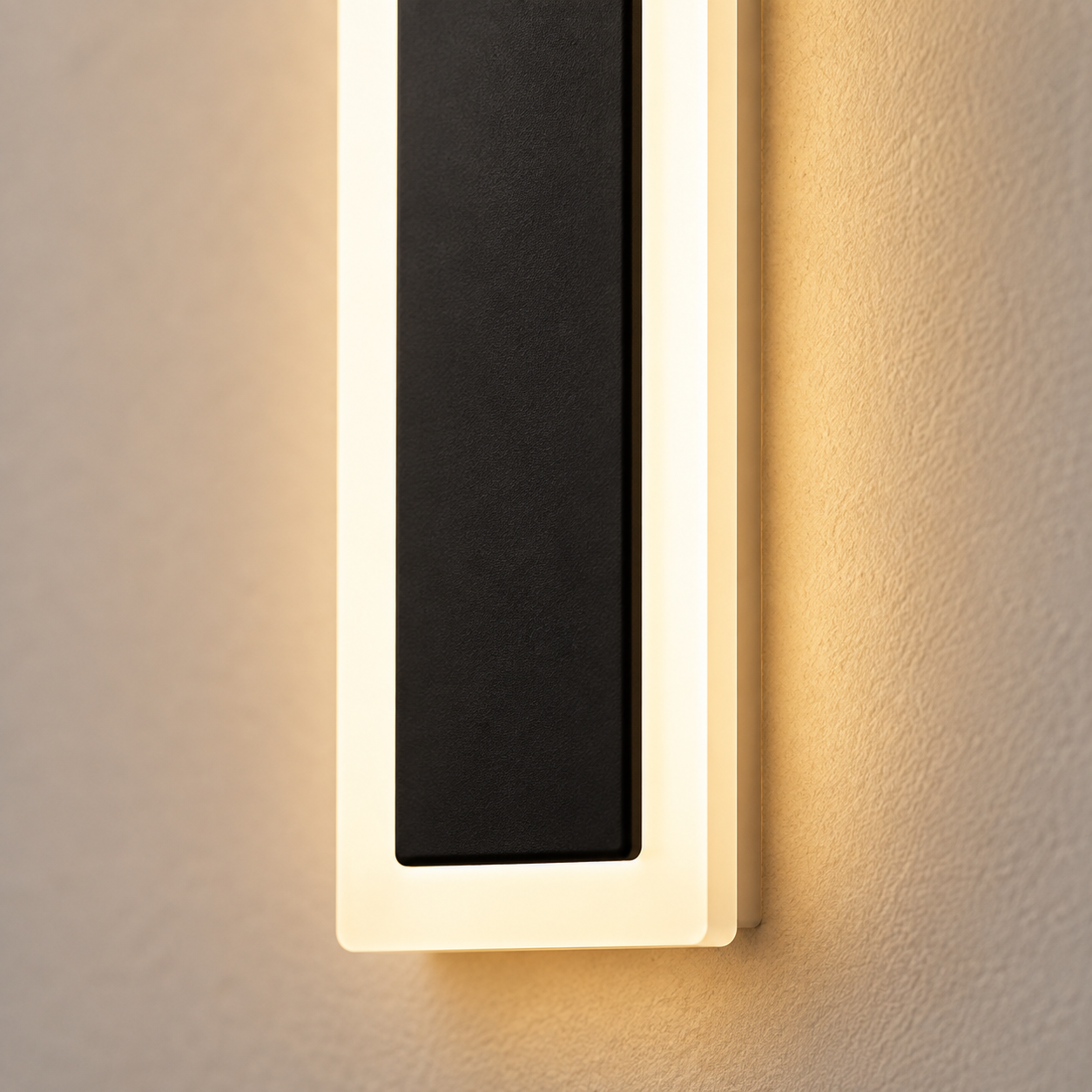 Outdoor wall sconce close-up showing a black center panel, pale frame, and warm side glow.