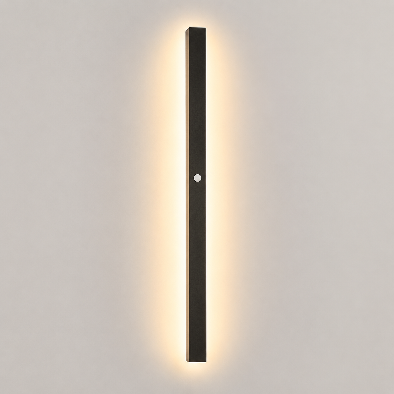 Outdoor wall sconce with a slim black body casting warm light on a pale wall.