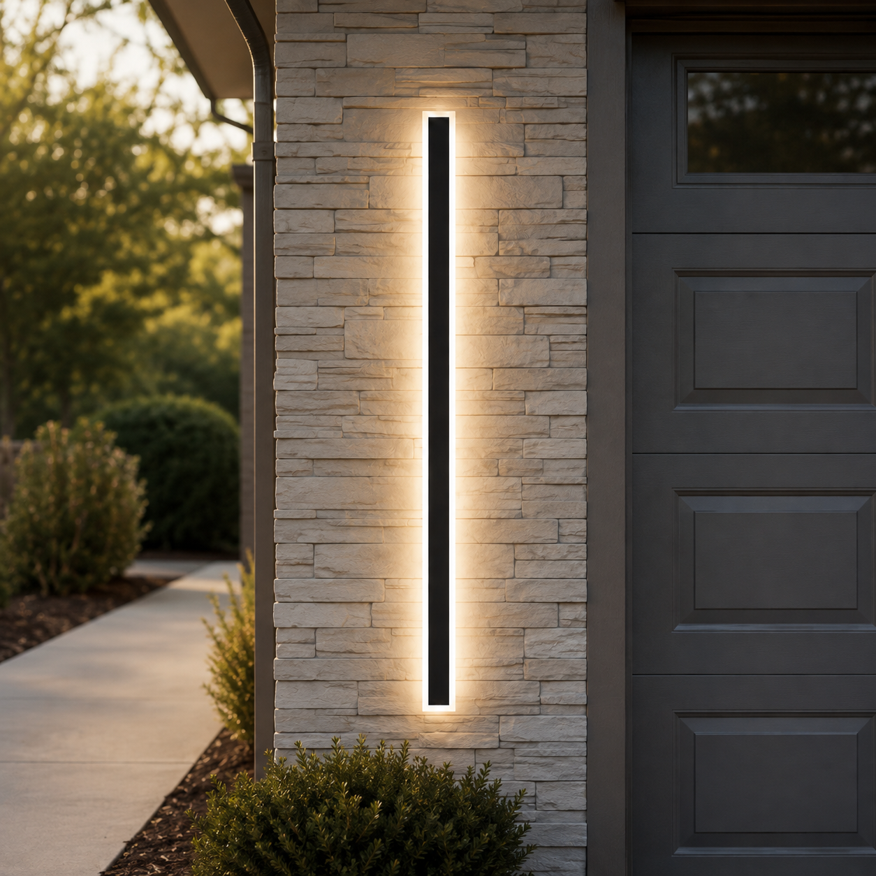 Outdoor wall sconce mounted on a brick entry wall beside a gray garage door.