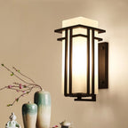 Black outdoor wall sconce beside a small display of ceramic vases.