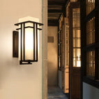 Black outdoor wall sconce mounted along a wood-framed passageway.
