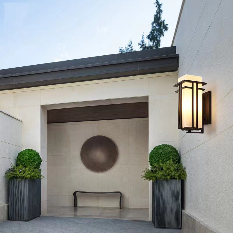 Black outdoor wall sconce illuminating a recessed courtyard entrance.