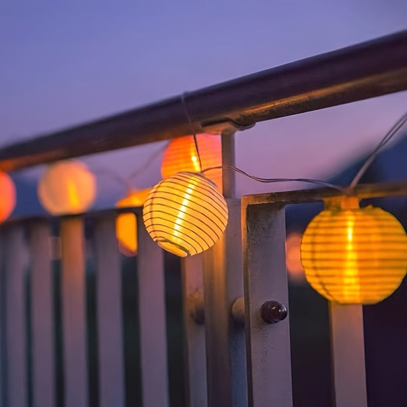Warm white paper lantern string lights hanging beneath a porch roof.