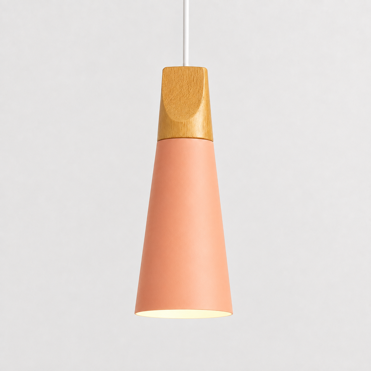 Pink cone pendant light with a natural wood accent, illuminated against a light gray background.