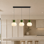 three green Bauhaus pendant light fixtures over a bright kitchen island