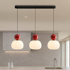 three red Bauhaus pendant light fixtures in a neutral kitchen