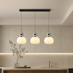 three silver Bauhaus pendant light fixtures over a bright backsplash