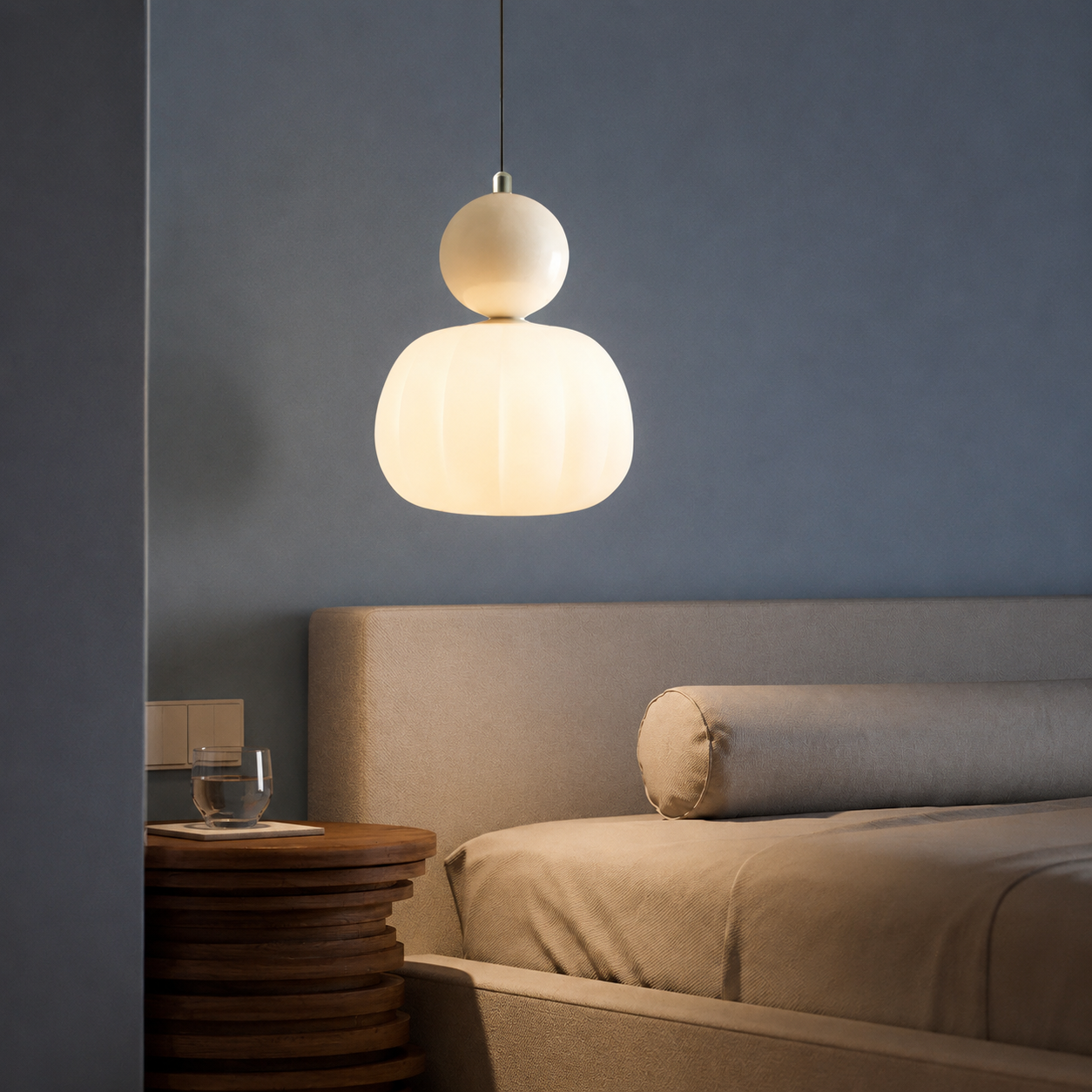 single beige Bauhaus pendant light glowing above a bedroom table