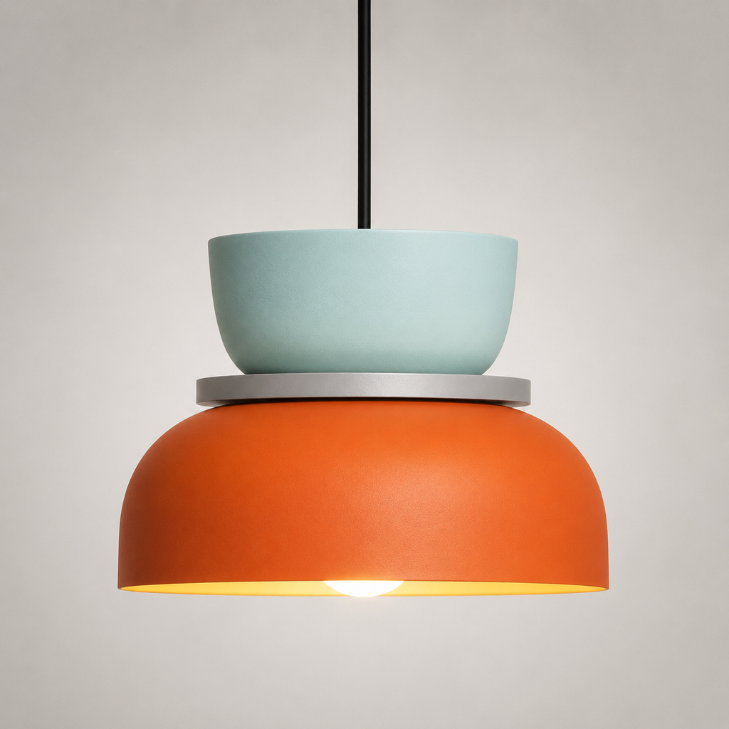 Orange and mint green color-block pendant light glowing warm white against a neutral studio background.