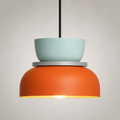Orange and mint green color-block pendant light glowing warm white against a neutral studio background.