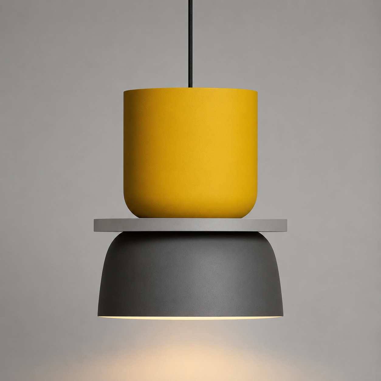 Yellow and gray color-block pendant light glowing warm white against a neutral studio background.