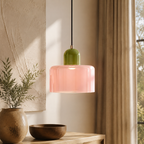 Single pink and green glass pendant light hangs beside a sunlit window.