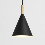 Black conical pendant light with a natural wood stem, glowing warm white against a neutral background.
