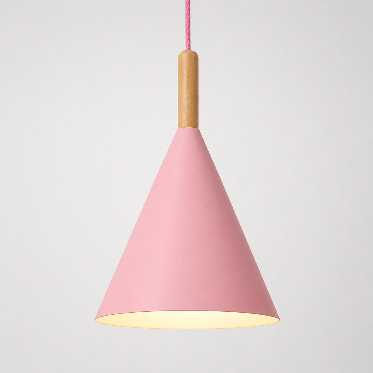 Pink conical pendant light with a natural wood stem, glowing warm white against a neutral background.
