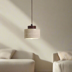 Pendant light with natural stone drum shade and dark walnut toned accent in a living space