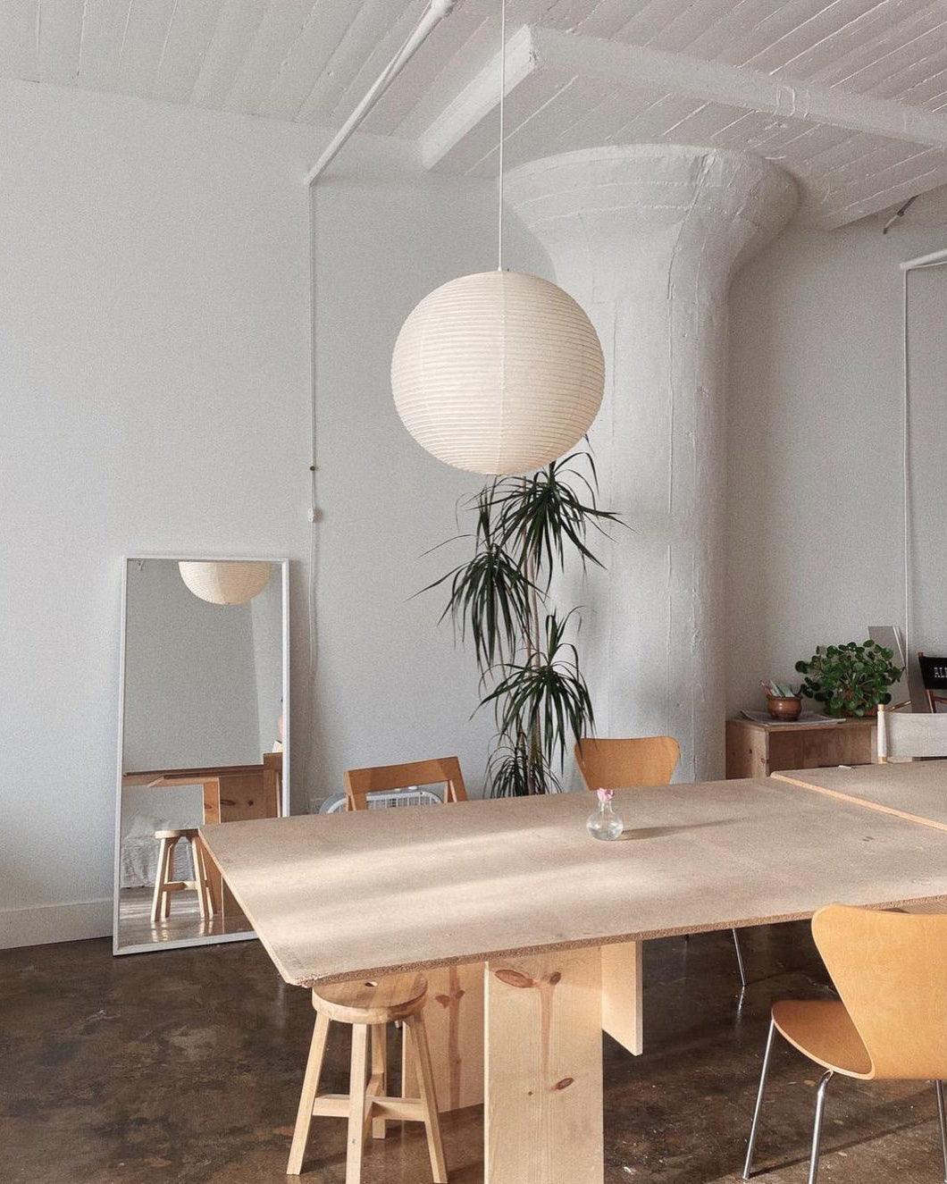 White paper globe pendant light hanging above a furnished living or dining space