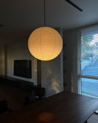 White paper globe pendant light hanging above a furnished living or dining space