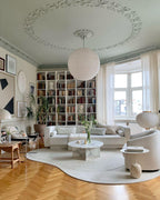 White paper globe pendant light hanging above a furnished living or dining space