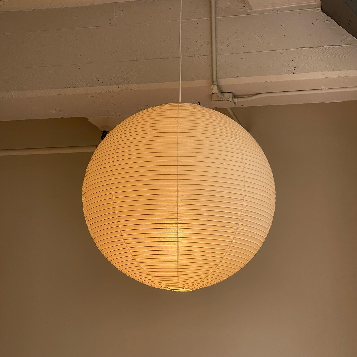 White paper globe pendant light hanging above a furnished living or dining space