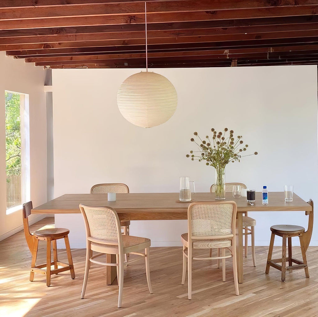 White paper globe pendant light hanging above a furnished living or dining space