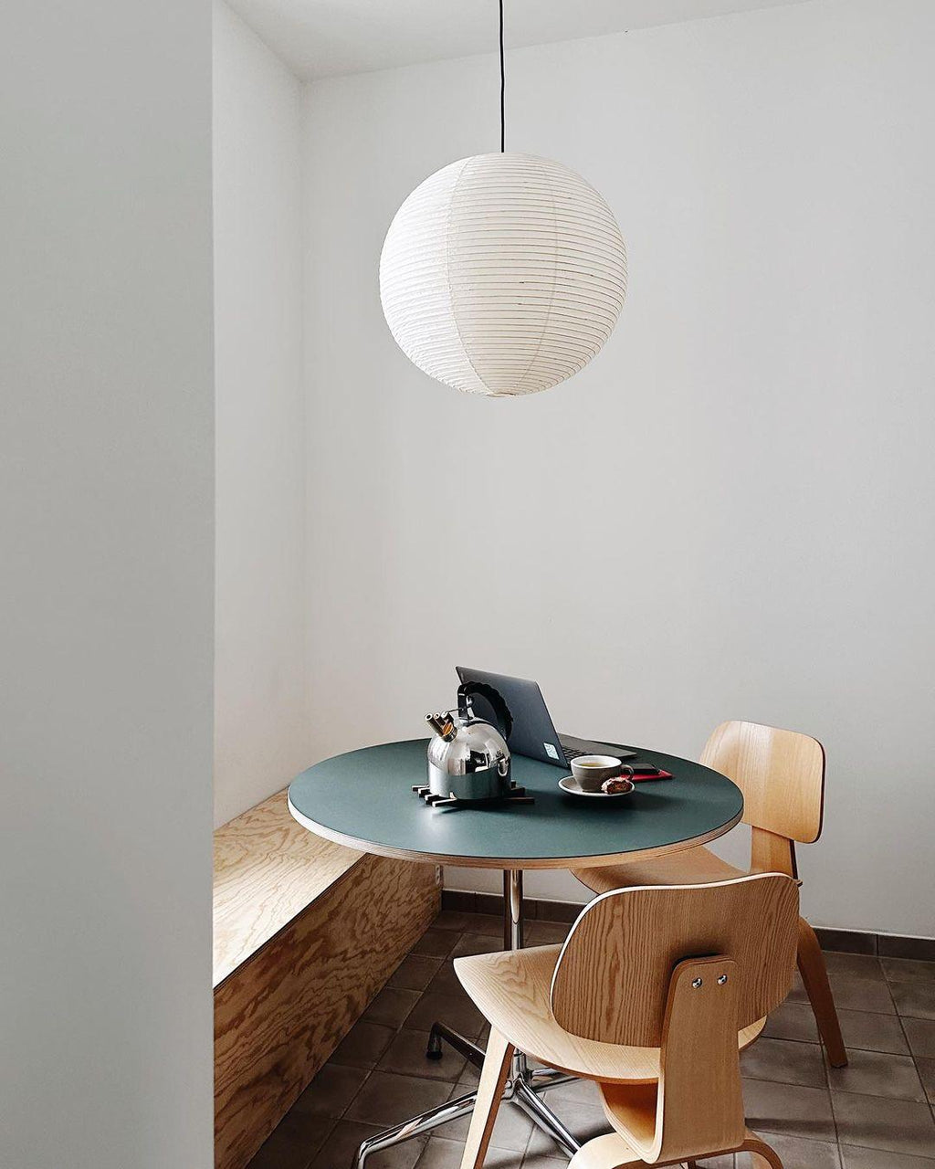 White paper globe pendant light hanging above a furnished living or dining space