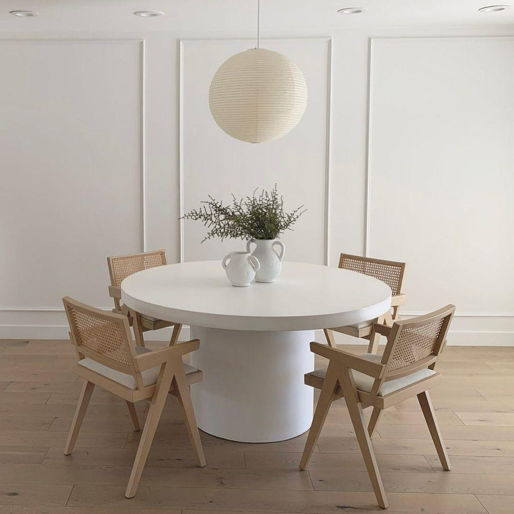 White paper globe pendant light hanging above a furnished living or dining space