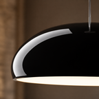 Close-up pendant light view showing the glossy black dome shade and white inner surface.