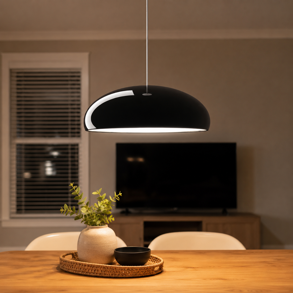 Black dome pendant light suspended above a wooden dining table in a warm interior.