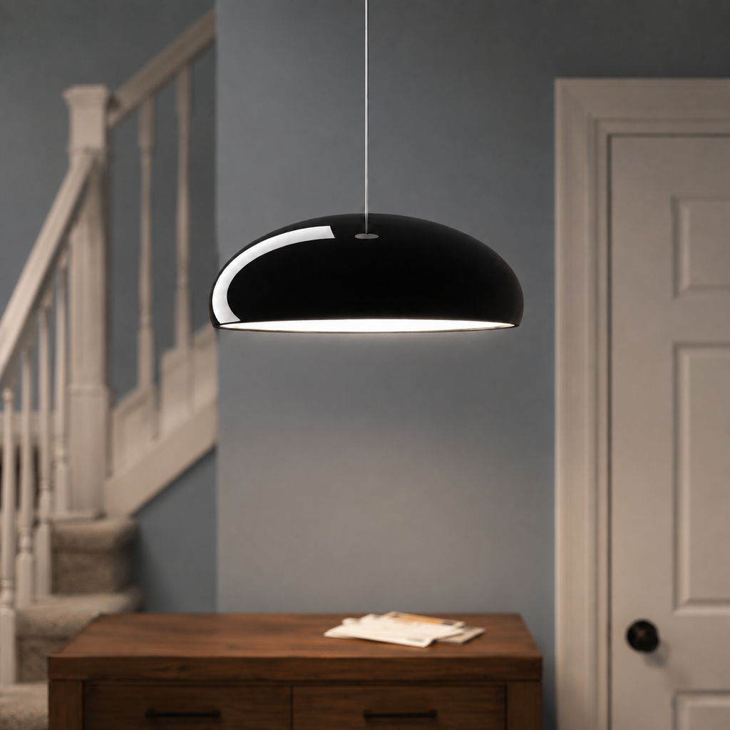Black dome pendant light suspended near a staircase above a small table.