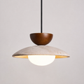 Pendant light with a wood accent, textured dome shade, and glowing round diffuser on a neutral background.