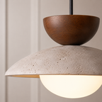 Close-up pendant light view showing the wood accent, textured shade, and glowing diffuser.