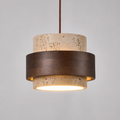 Pendant light with a round travertine and dark wood shade hanging against a light background with the light turned on.