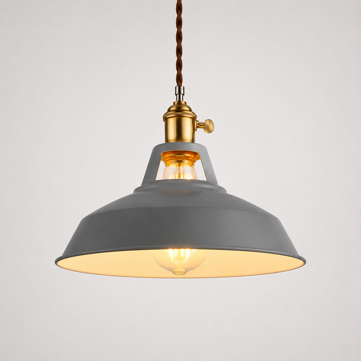 Metal pendant light with a brass socket, twisted brown cord, and exposed warm-glowing bulb.