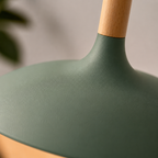 Close-up of a green wide-dome pendant light showing the textured aluminum shade and natural wood stem.
