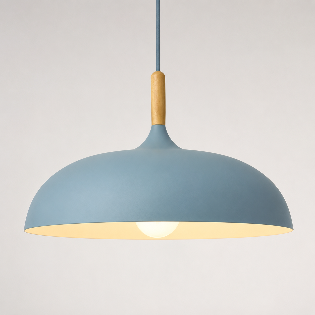 Blue wide-dome pendant light with a natural wood stem, glowing warm white against a neutral background.
