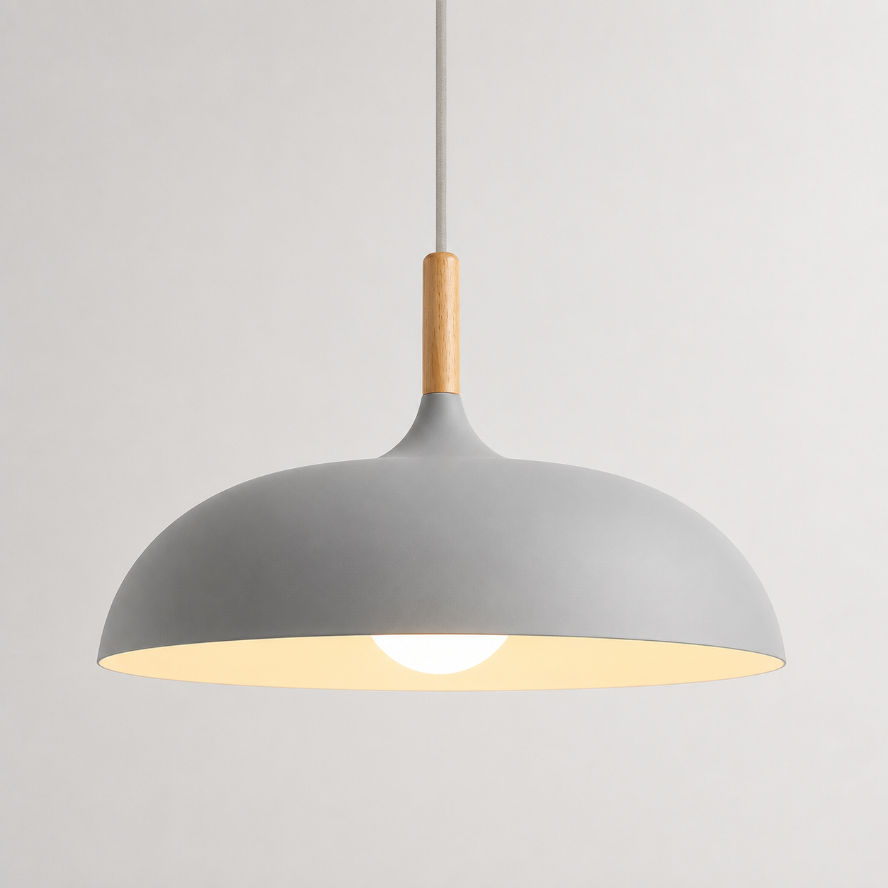 Gray wide-dome pendant light with a natural wood stem, glowing warm white against a neutral background.
