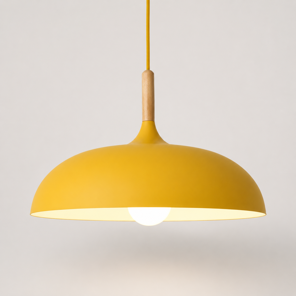 Yellow wide-dome pendant light with a natural wood stem, glowing warm white against a neutral background.
