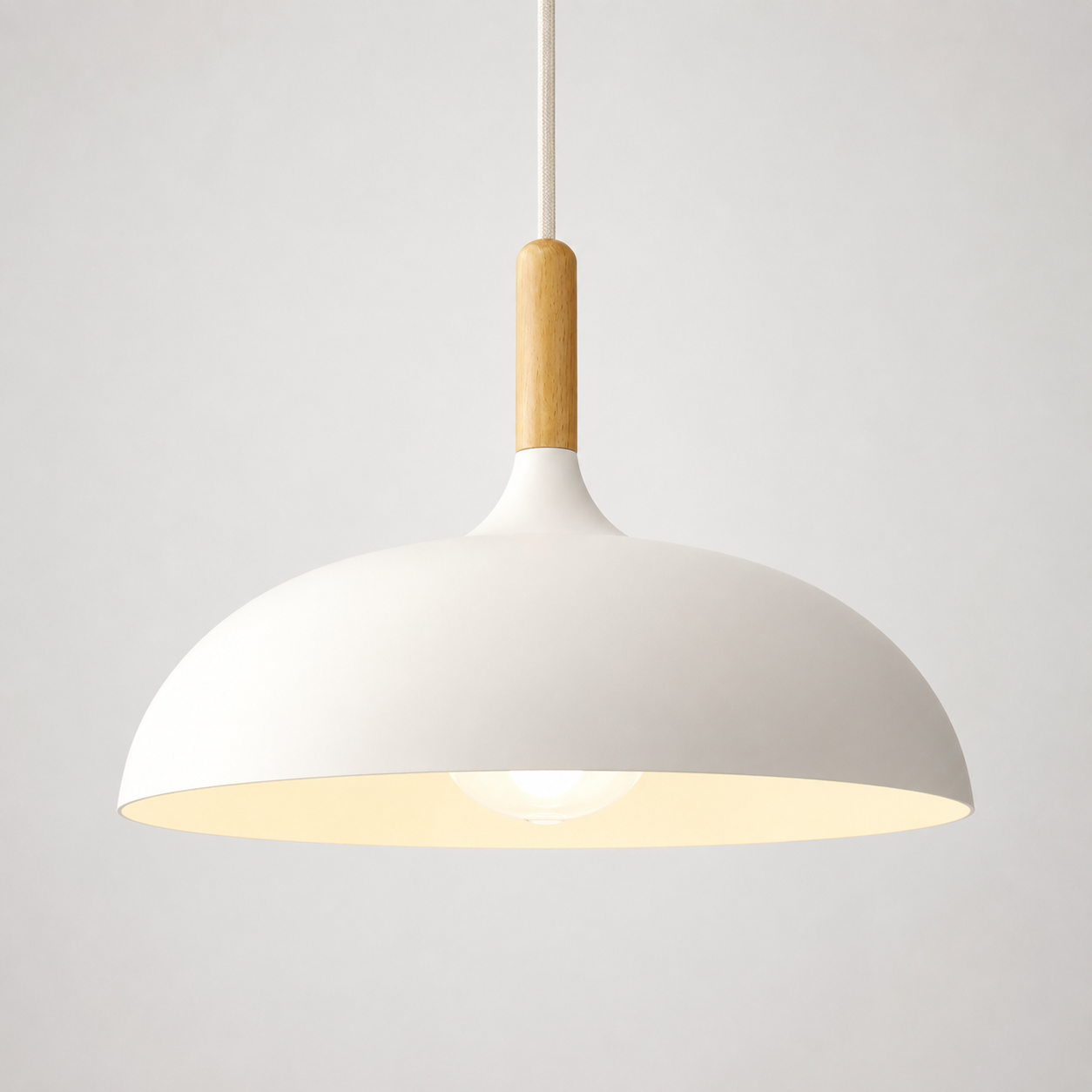 White wide-dome pendant light with a natural wood stem, glowing warm white against a neutral background.
