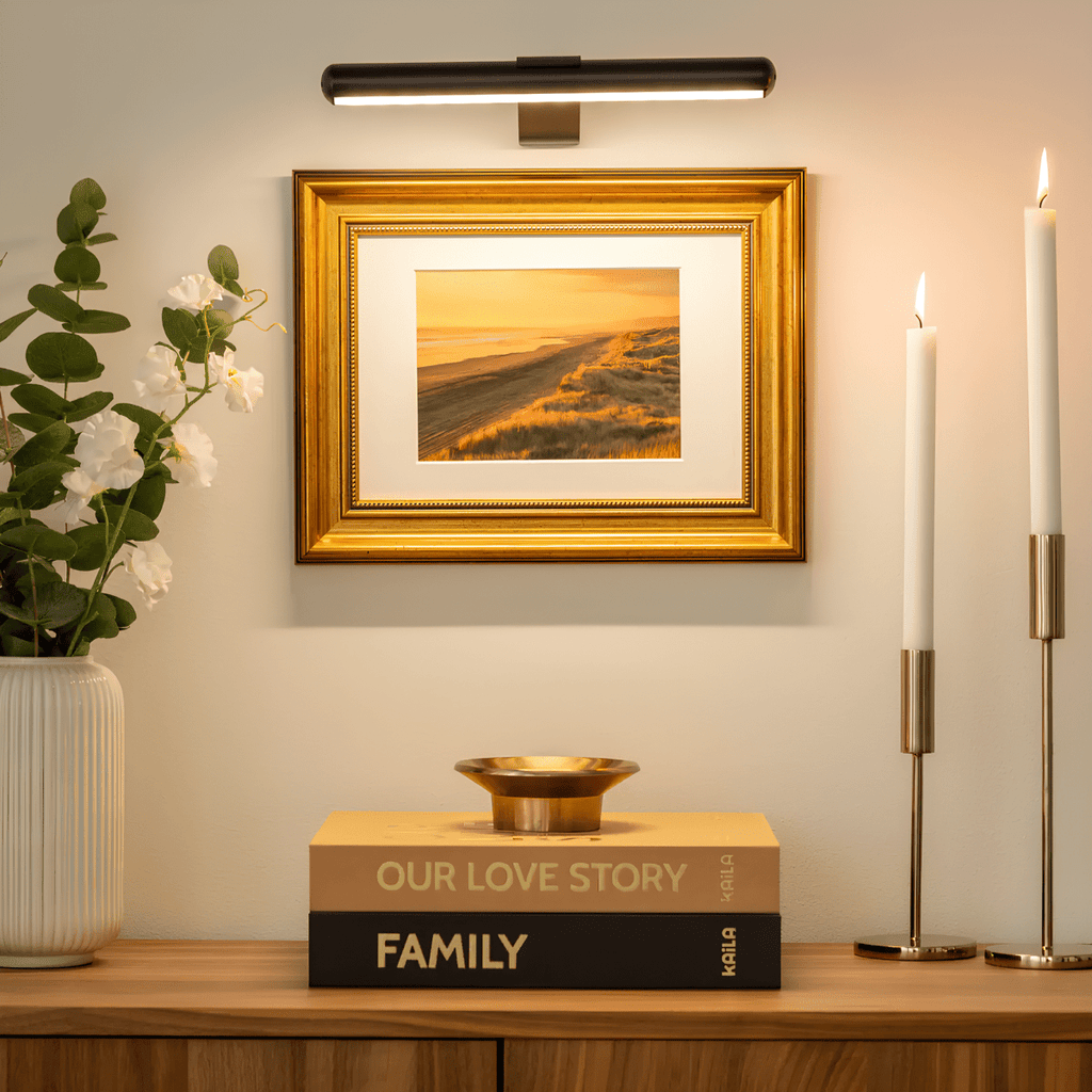 Black picture light illuminating framed artwork above a console.