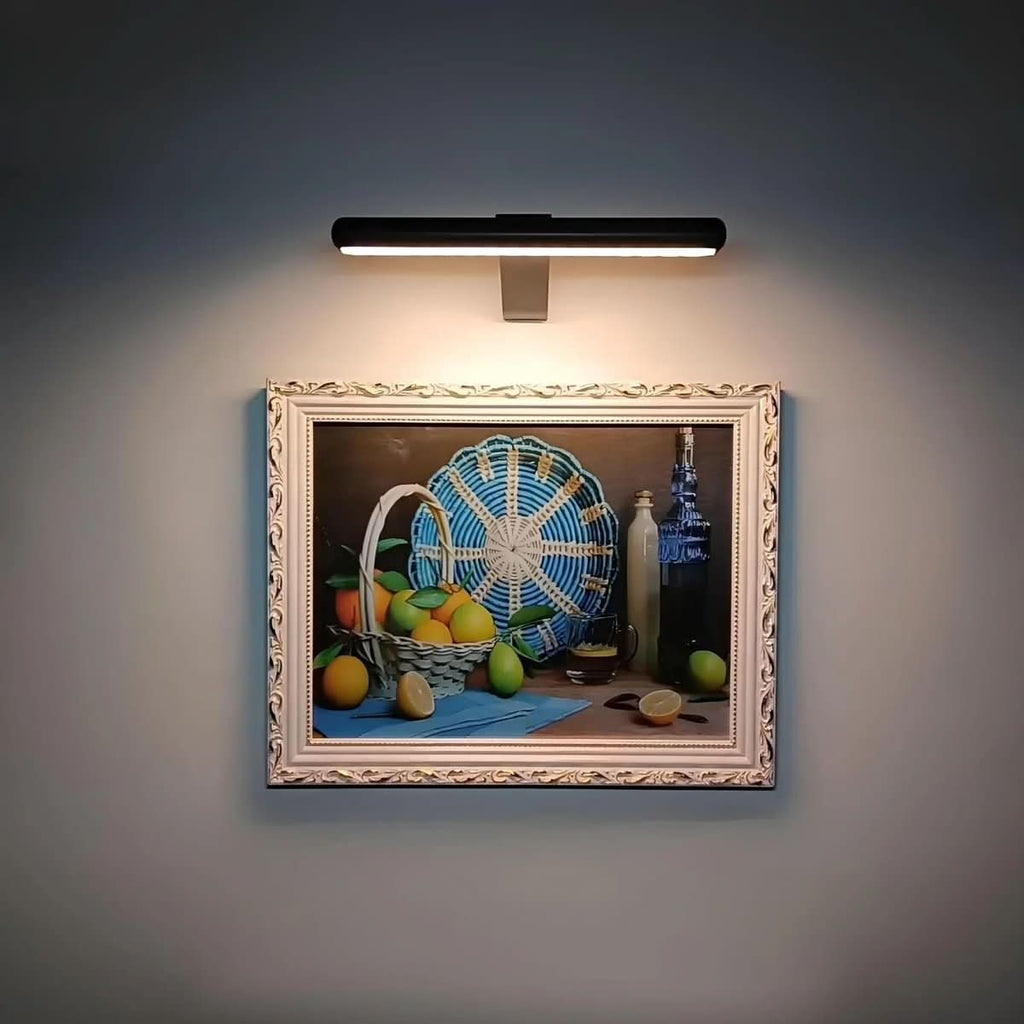 Black picture light illuminating a small colorful framed painting.