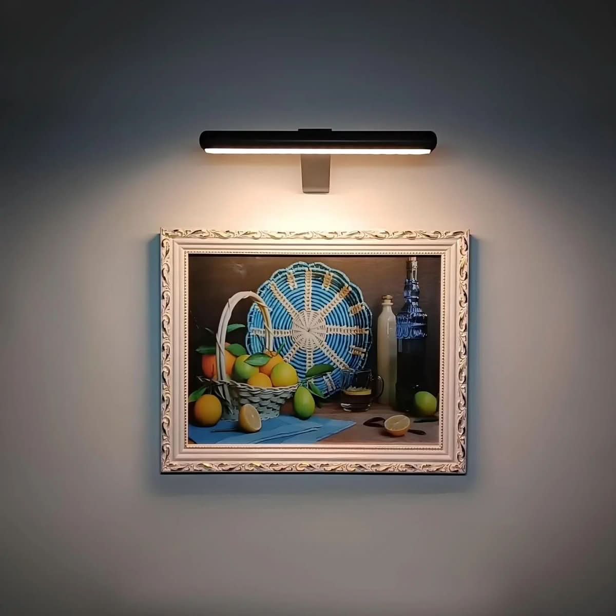 Black picture light illuminating a small colorful framed painting.