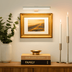 White picture light illuminating framed art above a console.